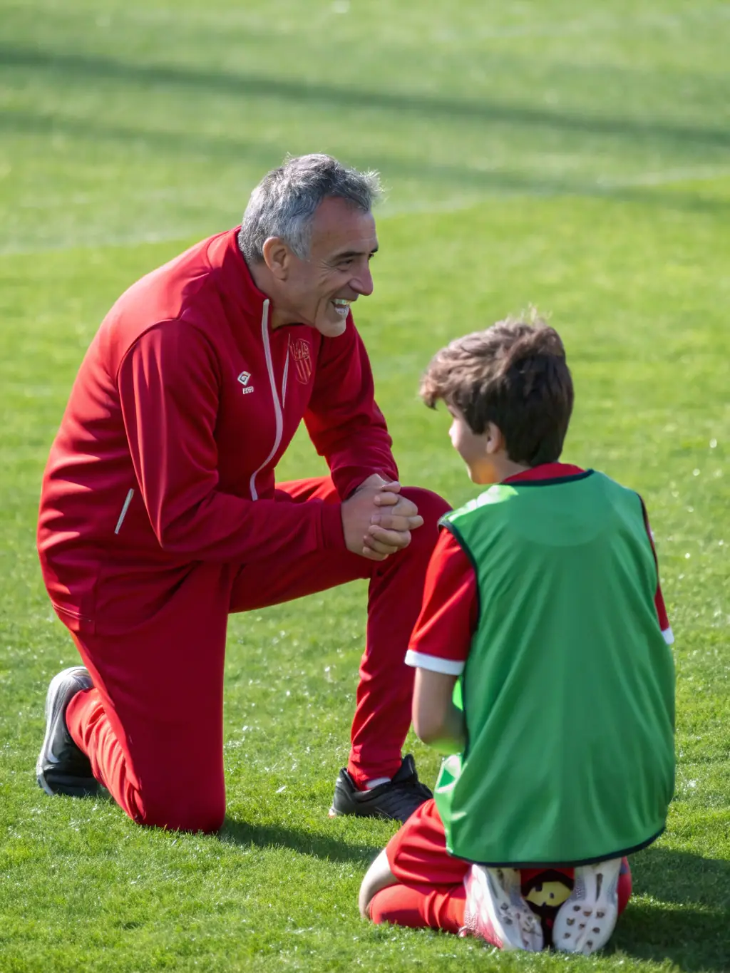 A coach mentoring young players during a football training session, highlighting guidance and skill development.